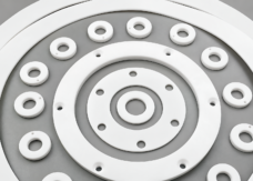 White PTFE flange gaskets with bolt holes and smaller drilled washers on a gray background; supplied by IKSONIC in China.