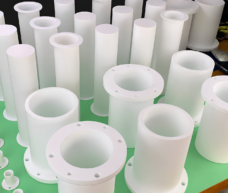 White PTFE flanged bushings and plain cylindrical sleeves viewed from above; supplied by IKSONIC in China.