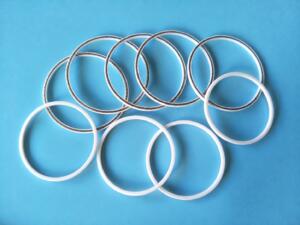 White IKSONIC seal rings and spring-equipped PTFE rings arranged on a blue background.