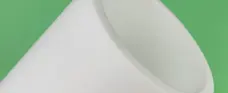 White PTFE sleeve close-up showing the open bore, rim and cylindrical wall; supplied by IKSONIC in China.