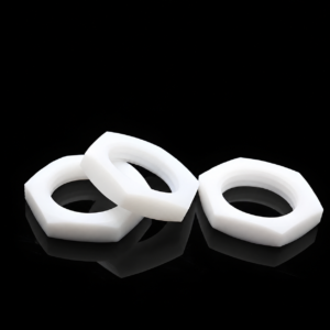 Three white IKSONIC PTFE thin hex nuts on a reflective black surface, with one tilted to show its low-profile edge.
