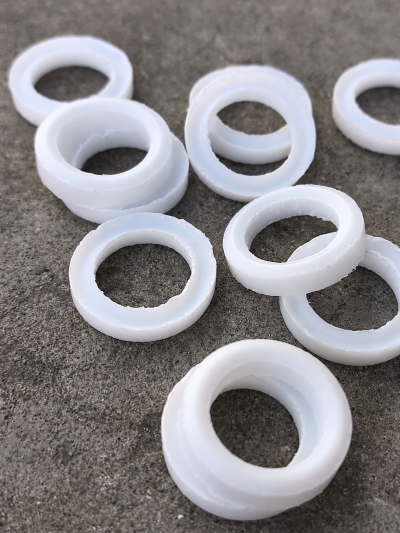 iksonic-ptfe-v-packing-rings-supplier IKSONIC PTFE V-packing rings showing rough machined edges on a gray surface.