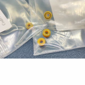 Four IKSONIC yellow pump plunger seals on clear packaging, three showing metal spring inserts and one showing the reverse face.