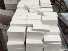 Stacks of rectangular white alumina ceramic liner blocks manufactured by IKSONIC.