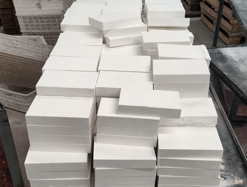 Stacks of rectangular white alumina ceramic liner blocks manufactured by IKSONIC.