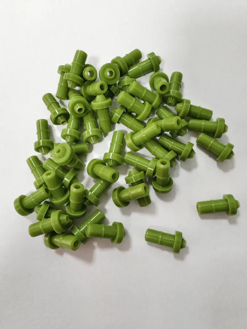 Green rubber dispensing nozzle assortment showing open bores and profiles, available wholesale from IKSONIC.