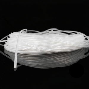 Coiled IKSONIC transparent silicone capillary tubing on a black reflective surface, with one open tube end visible.