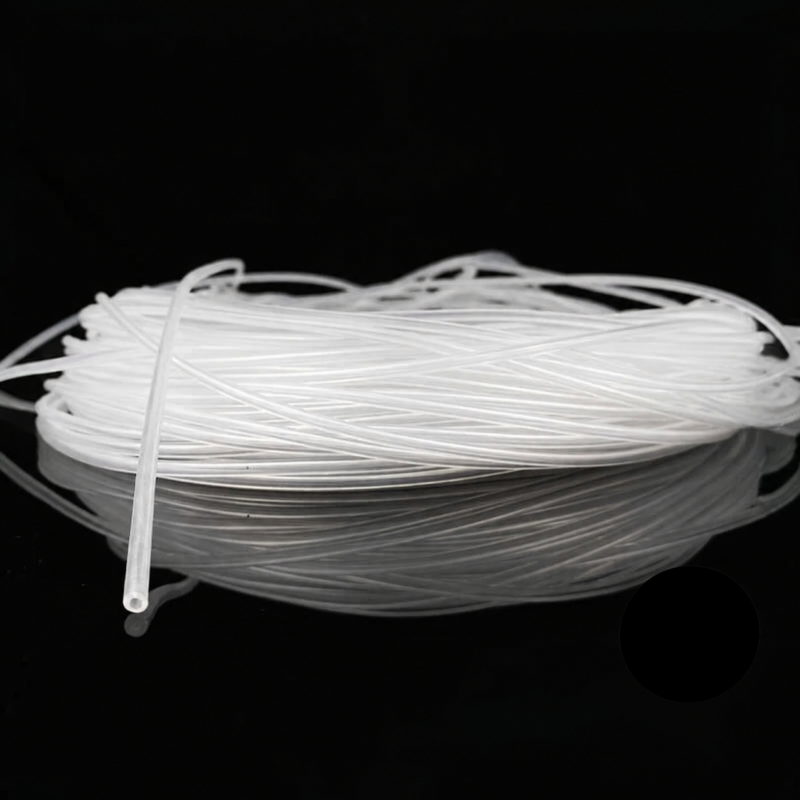 Coiled transparent silicone capillary tubing on a black reflective surface, with one open tube end visible.