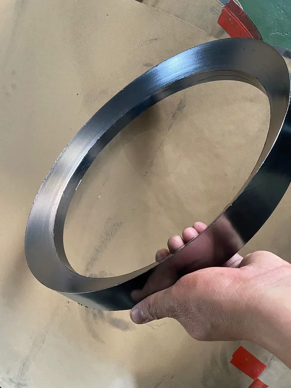 Large smooth-faced graphite packing ring held at an angle above a cardboard surface.