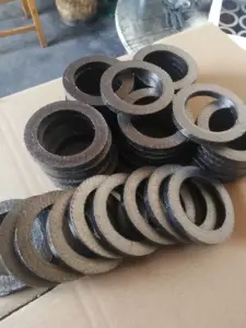 Assorted IKSONIC graphite packing rings arranged in stacks and overlapping rows on a cardboard surface.