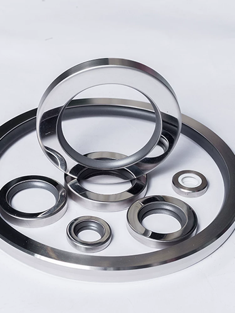 iksonic-supplier-stainless-steel-ptfe-oil-seals-assortment Assortment of stainless-steel PTFE oil seals in several sizes on a white surface, supplied by IKSONIC in China.