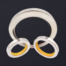 Three stainless-steel oil seals on a charcoal background, with one large black-lipped ring behind two smaller yellow-lipped rings, supplied by IKSONIC in China.