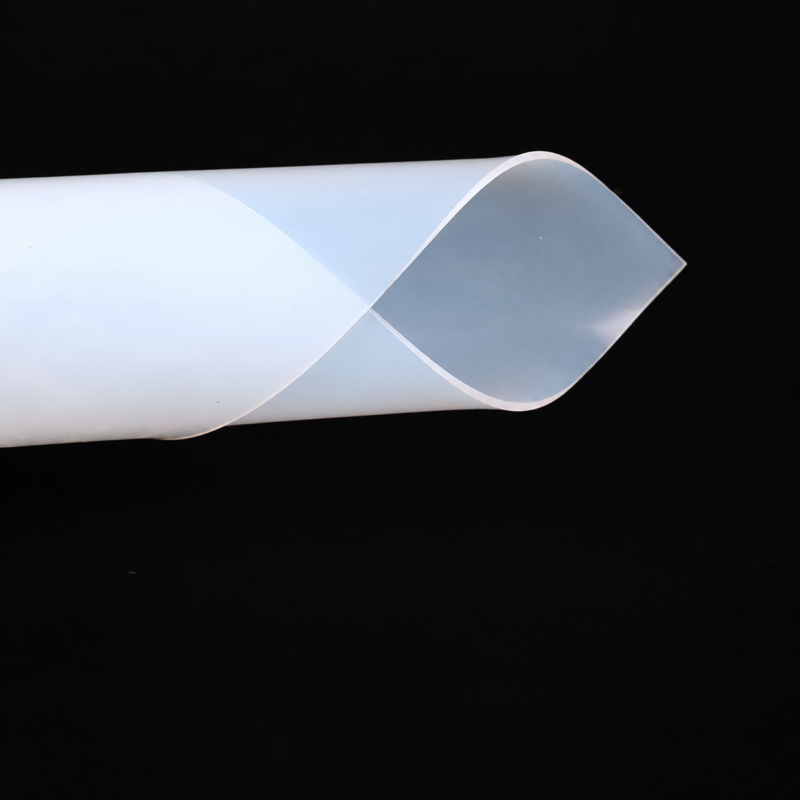Translucent silicone rubber sheet curved into an overlapping loop on a black background; available through IKSONIC.