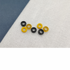 IKSONIC supplier photograph of seven black and yellow plunger seals in a clustered arrangement, showing center holes and spring-facing and reverse-facing surfaces.