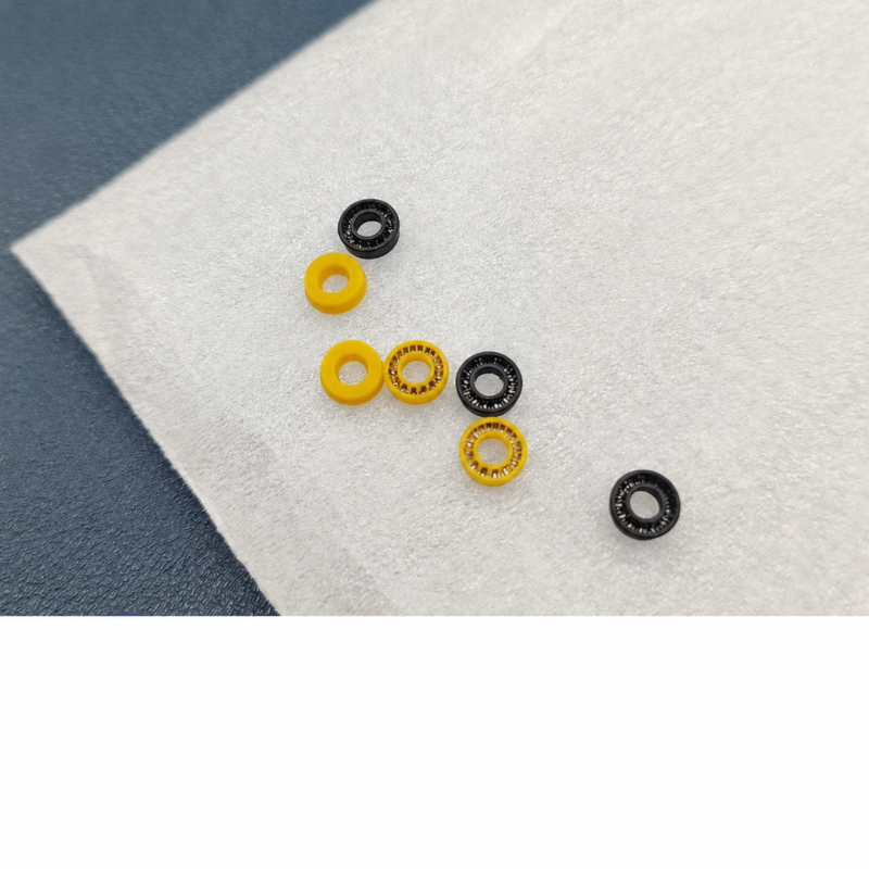 IKSONIC supplier photograph of seven black and yellow plunger seals spaced on a light surface, showing center holes and spring-facing and reverse-facing surfaces.