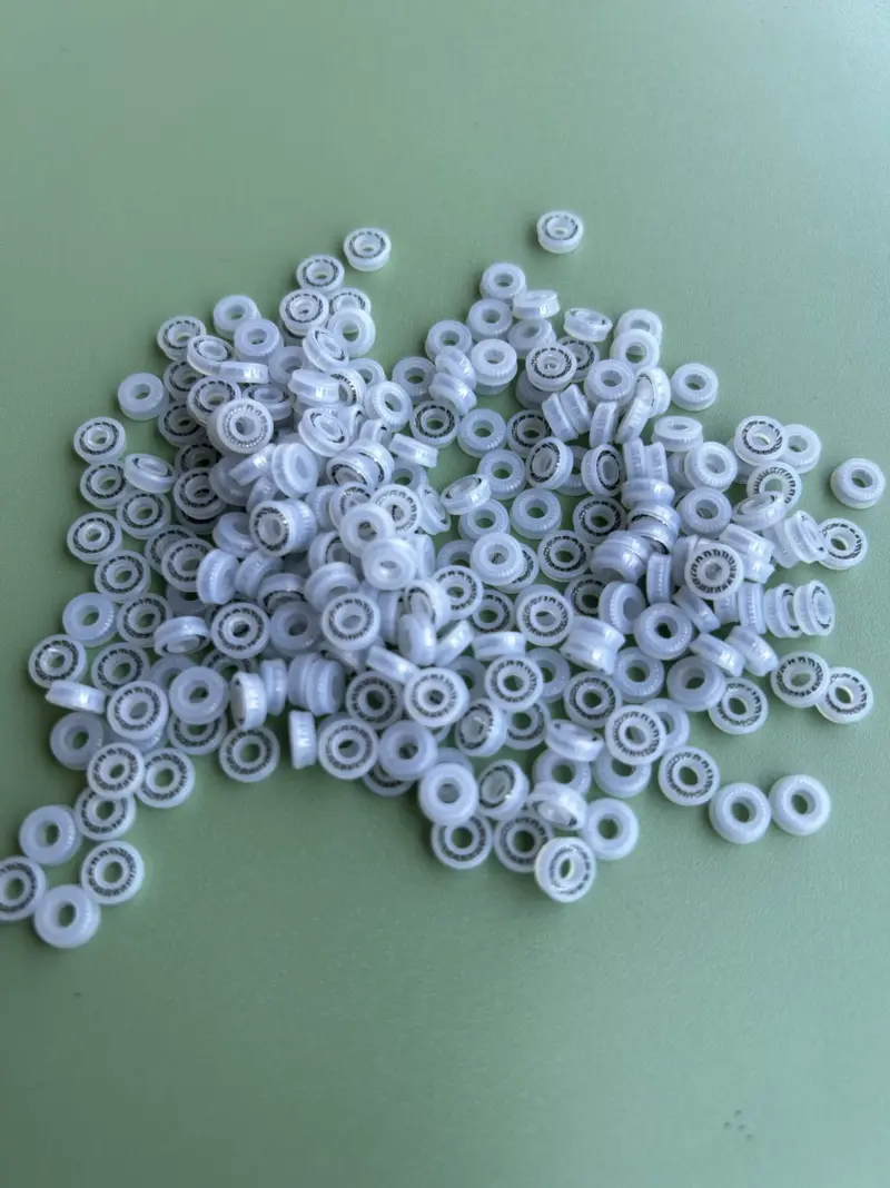 Jetting valve seals 3 x 6 x 2.4 size code Small translucent white jetting valve seals with metal springs on a green surface.