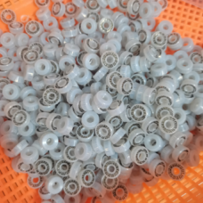 Close view of translucent white annular jetting valve seals with visible metal spring inserts in an orange basket.