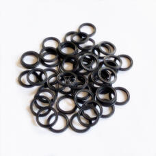 Overlapping small black sealing rings with grooved profiles on a white surface.