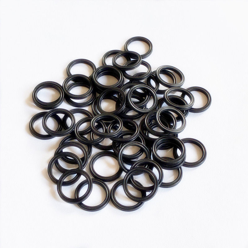 Overlapping small black sealing rings with grooved profiles on a white surface.