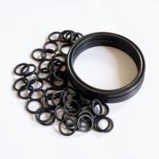 Black sealing rings in assorted sizes next to a stack of larger rings on a white surface.