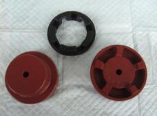 Black flexible coupling insert beside two red metal coupling hubs, shown as an assembly reference.