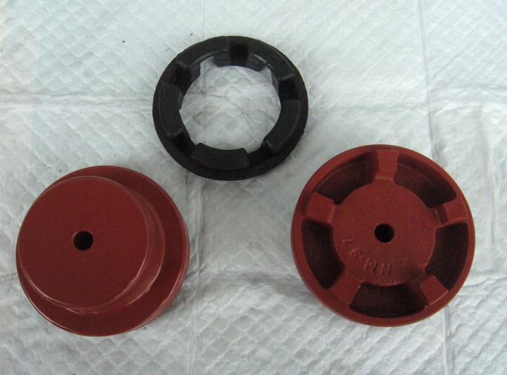 Black flexible coupling insert beside two red metal coupling hubs, shown as an assembly reference.