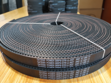 Top view of a coiled open-ended timing belt showing the tooth pattern, printed markings and white binding ties.