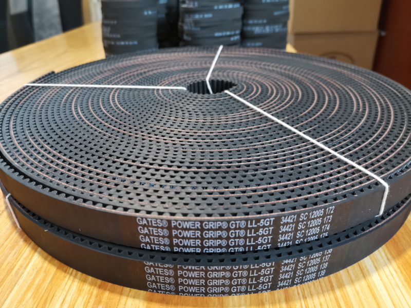 Top view of a coiled open-ended timing belt showing the tooth pattern, printed markings and white binding ties.