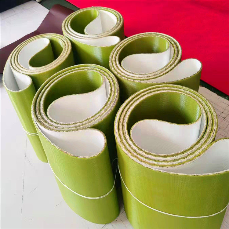Five coils of wide green flat belts with pale inner faces on a work surface.