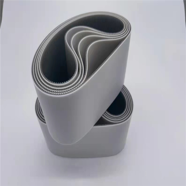 Two stacked coils of wide grey belts showing their smooth outer faces and toothed inner surfaces.
