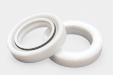 Two overlapping white TC rotary shaft seals with the spring and inner lip visible on the front seal.