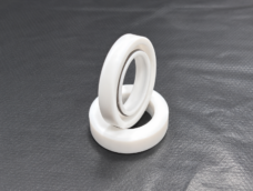 One white TC rotary shaft seal standing in a second seal on a dark textured surface.
