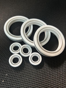 White shaft seals in several sizes with metal springs visible on a dark textured surface.