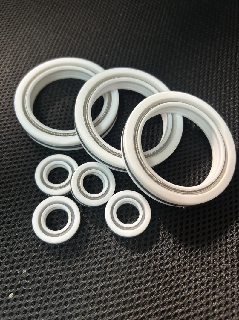 White shaft seals in several sizes with metal springs visible on a dark textured surface.