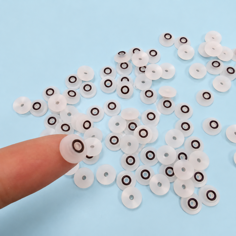 Small translucent white cylindrical seals with dark concentric rings, including one held on a fingertip.