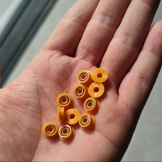 Small yellow flanged seals resting in an open palm, showing plain faces and exposed circular metal springs.