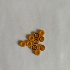 Ten small yellow annular seals on a pale textured surface, with plain and spring-facing sides visible.